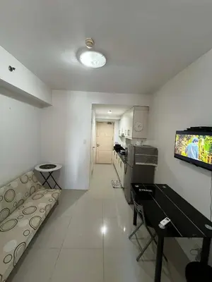 a living room with a couch and a tv on the wall at Sea Residences Vertex in Manila