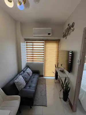 a living room with a black leather couch and a table at 2 bedroom modern unit in Manila