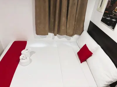 a white bed with red pillows in a room at City Stay Inns Slex Makati in Manila