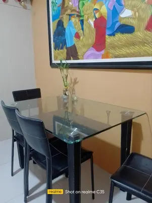 a glass table with chairs and a painting on the wall at Kaoru Properties in Manila