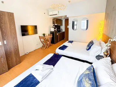 two beds in a large room with a kitchen at Destiny Hotel - 1601 in Manila