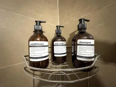 three bottles of soap sitting on a shelf at Destiny Hotel - 1601 in Manila