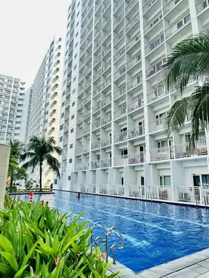 a large building with a swimming pool in front of it at Cg's Staycations in Manila