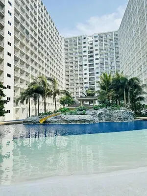 a large swimming pool with palm trees and buildings at Cg's Staycations in Manila