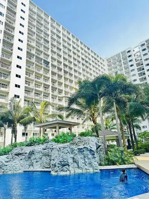 a man in a swimming pool in front of a large building at Cg's Staycations in Manila
