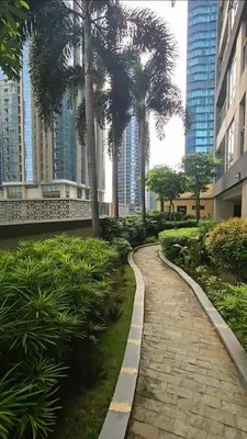a walkway in a park with palm trees and buildings at Hygge-ParkWest BGC near Grand Hyatt & Mitsukoshi in Manila