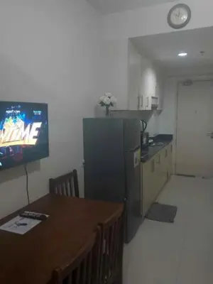 a kitchen with a table and a tv in a room at Pasay Staycation across MOA in Manila