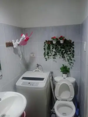 a bathroom with a toilet and a sink and plants at Pasay Staycation across MOA in Manila