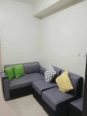 a couch with four pillows on it in a room at Pasay Staycation across MOA in Manila