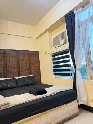a bedroom with a large bed with a window at Stamford Studio Condo in McKinley Hill, BGC Taguig in Manila