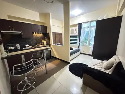 a living room with a couch and a kitchen at Stamford Studio Condo in McKinley Hill, BGC Taguig in Manila