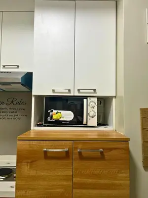 a microwave oven sitting on top of a wooden cabinet at City Comfort Studio at Sunshine 100 in Manila