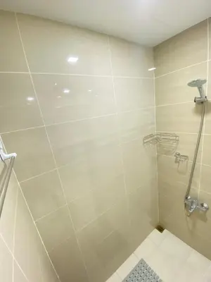 a bathroom with a shower with a glass door at La Rosa Home - Uptown BGC in Manila