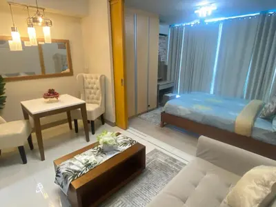 a living room with a bed and a table at La Rosa Home - Uptown BGC in Manila