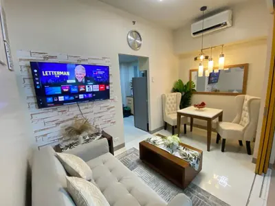 a living room with a couch and a tv at La Rosa Home - Uptown BGC in Manila