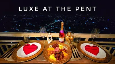 a table with two plates of food and wine glasses at The Luxe at The Pent in Manila