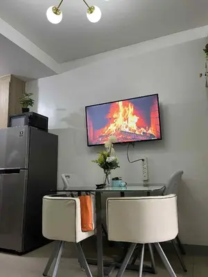 a dining room with a table and a television on the wall at Shore 2 residences tower 1 in Manila