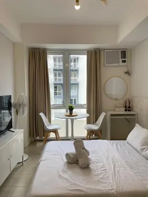 a bedroom with a white bed and a table and chairs at Kasara Staycation Pasig in Manila