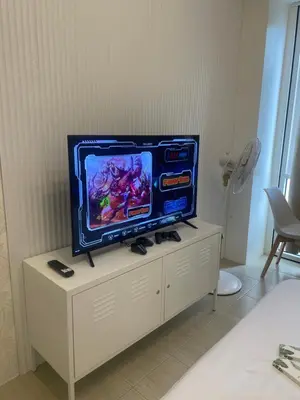 a tv sitting on top of a white cabinet at Kasara Staycation Pasig in Manila