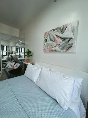 a bedroom with a bed with a painting on the wall at Pleasant Air Residences With Balcony and Fast Wi-Fi in Manila