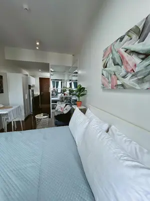 a bedroom with a white bed with a painting on the wall at Pleasant Air Residences With Balcony and Fast Wi-Fi in Manila