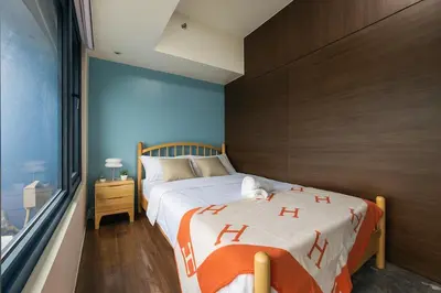 a bedroom with a bed with an orange and white blanket at 2BR Air Residence, Makati City in Manila