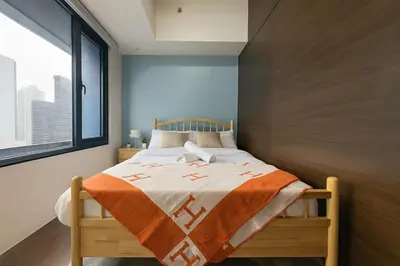 a bedroom with a bed with an orange and white blanket at 2BR Air Residence, Makati City in Manila