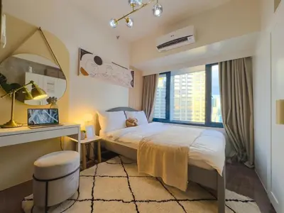 a bedroom with a bed and a desk and a window at 1BR Makati, Air Residences M010 in Manila