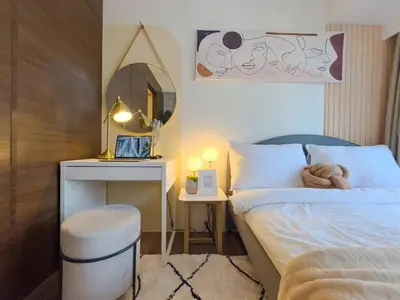a bedroom with a bed with a stool and a mirror at 1BR Makati, Air Residences M010 in Manila