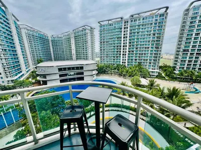 a balcony with two stools and some tall buildings at Azure Urban Resort Residences Parañaque City near NAIA Airport in Manila