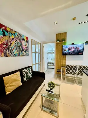 a living room with a black couch and a tv at Azure Urban Resort Residences Parañaque City near NAIA Airport in Manila
