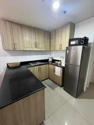a kitchen with wooden cabinets and a stainless steel refrigerator at 2 Bedroom Shore Residence Mall Of Asia Complex in Manila