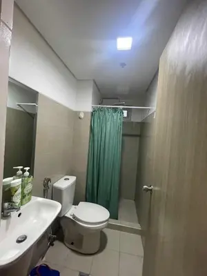 a bathroom with a toilet and a green shower curtain at 2 Bedroom Shore Residence Mall Of Asia Complex in Manila