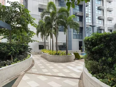 a courtyard with palm trees in front of a building at Panoramic Views 2BR Family Stay in Mckinley BGC in Manila