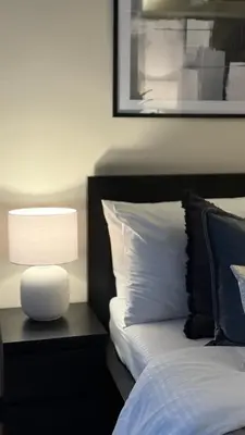 a bedroom with a bed with a lamp next to it at Luxe and Modern 1BR Unit in BGC in Manila