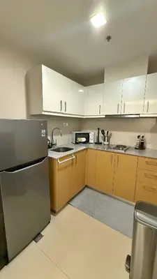 a kitchen with white cabinets and a stainless steel refrigerator at Luxe and Modern 1BR Unit in BGC in Manila