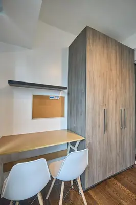 a desk and two chairs next to a wooden cabinet at Cozy Crib at Acqua Residences - Rockwell Views in Manila