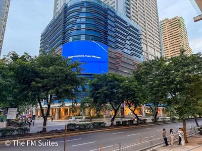 a tall building with a blue sign on the side of it at Cozy and Spacious Fast WiFi FREE Access Pool and Gym in Manila