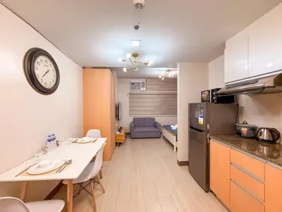 a kitchen with a table and a clock on the wall at Cozy and Spacious Fast WiFi FREE Access Pool and Gym in Manila