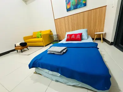 a bedroom with a blue bed and a yellow couch at Semi Furnished Condo at Sta Rosa Zadia Tower 2 in Sampong