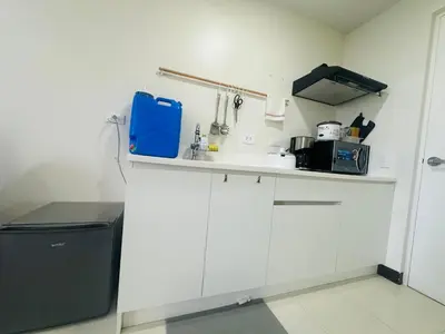 a kitchen with white cabinets and a blue bag on a counter at Semi Furnished Condo at Sta Rosa Zadia Tower 2 in Sampong