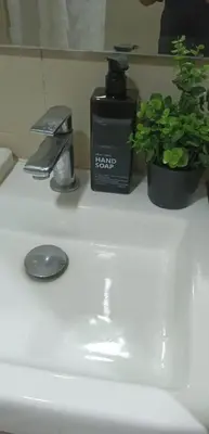 a bathroom sink with a soap dispenser and a plant at AR Pahinga Place - The Pause House in Manila