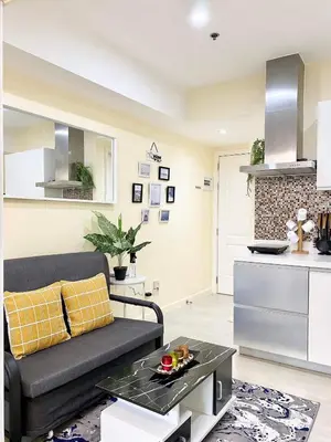 a living room with a couch and a kitchen at Positano Tower Beach view with PS4 - Azure Parañaque Resort in Manila