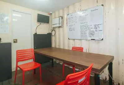 a table with red chairs and a white board on a wall at CitiHub Shaw Santa Mesa in Manila