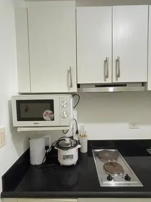 a kitchen with a microwave and a stove top oven at Jazz Luxe Getaway in Manila