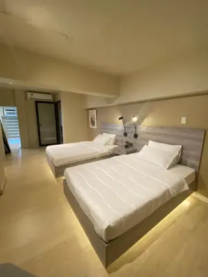 two beds in a hotel room with white sheets at EDSA Heights Penthouse Unit 3306 Ama Tower Residences in Manila