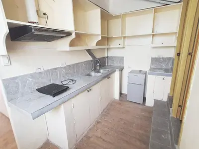 a small kitchen with white cabinets and a sink at Nemar Building Solo Room w AC in Manila