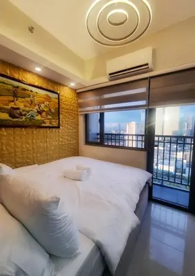 a bedroom with a large white bed with a large window at Luxe Studio at Fame Residences Malls, CBDs and More in Manila
