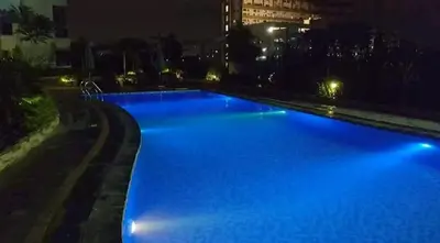 a large swimming pool with blue lights at night at 1 BR Luxury Apartment in Manila