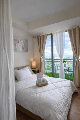 a bedroom with a large white bed with a window at Staycation in Diamond in Manila